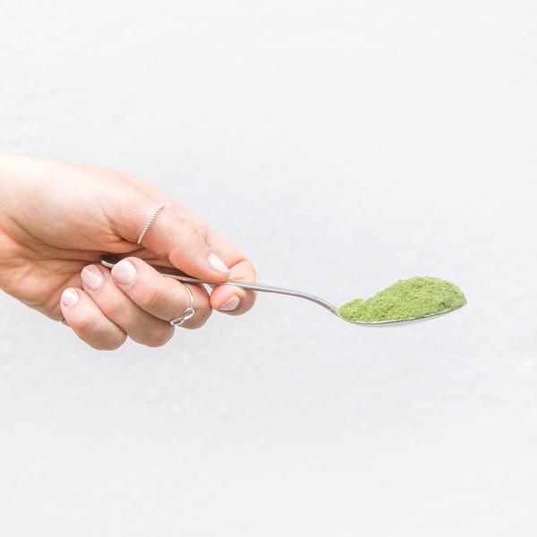 lady holding silver spoon of your superfoods super green mix